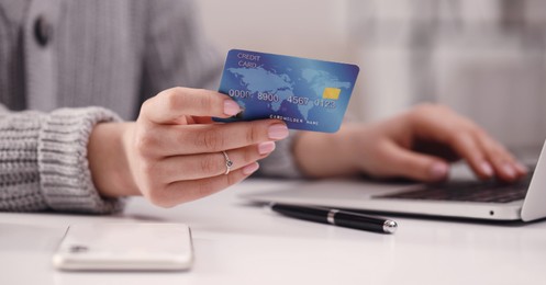 Woman with credit card using laptop for online payment at table, closeup. Banner design