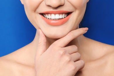 Photo of Young woman wearing beautiful lipstick on color background, closeup