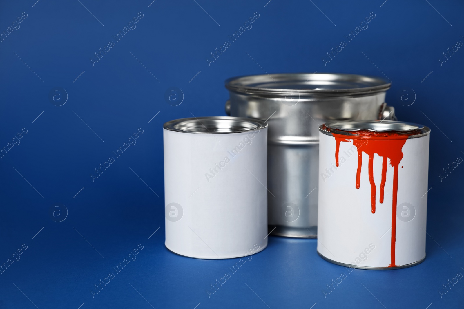 Photo of Cans of orange paint on blue background. Space for text