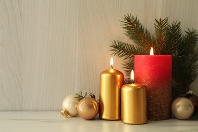 Photo of Burning candles with Christmas baubles and fir tree branch on table against wooden background. Space for text