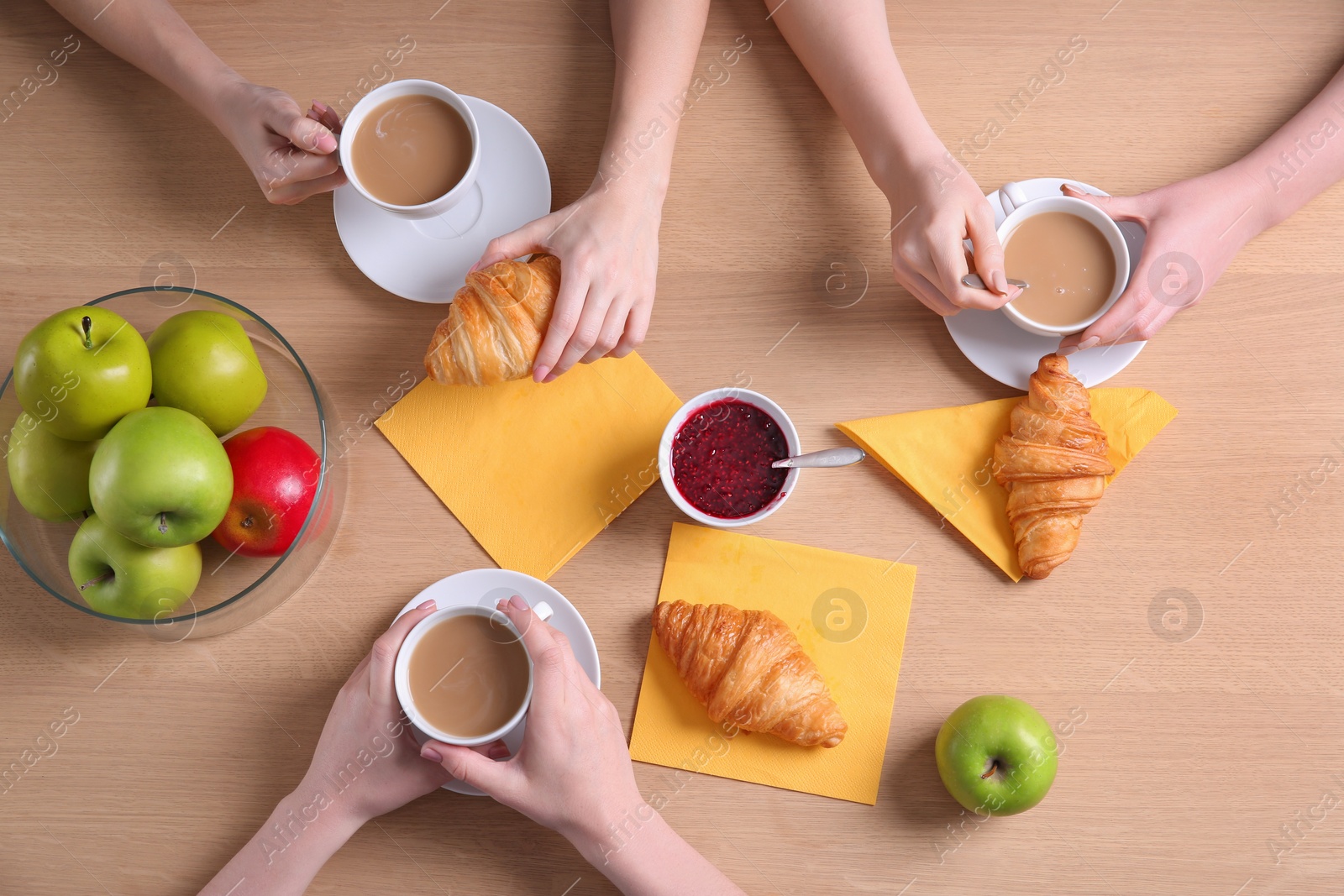 Photo of Women having tasty breakfast with fresh croissants at table, top view