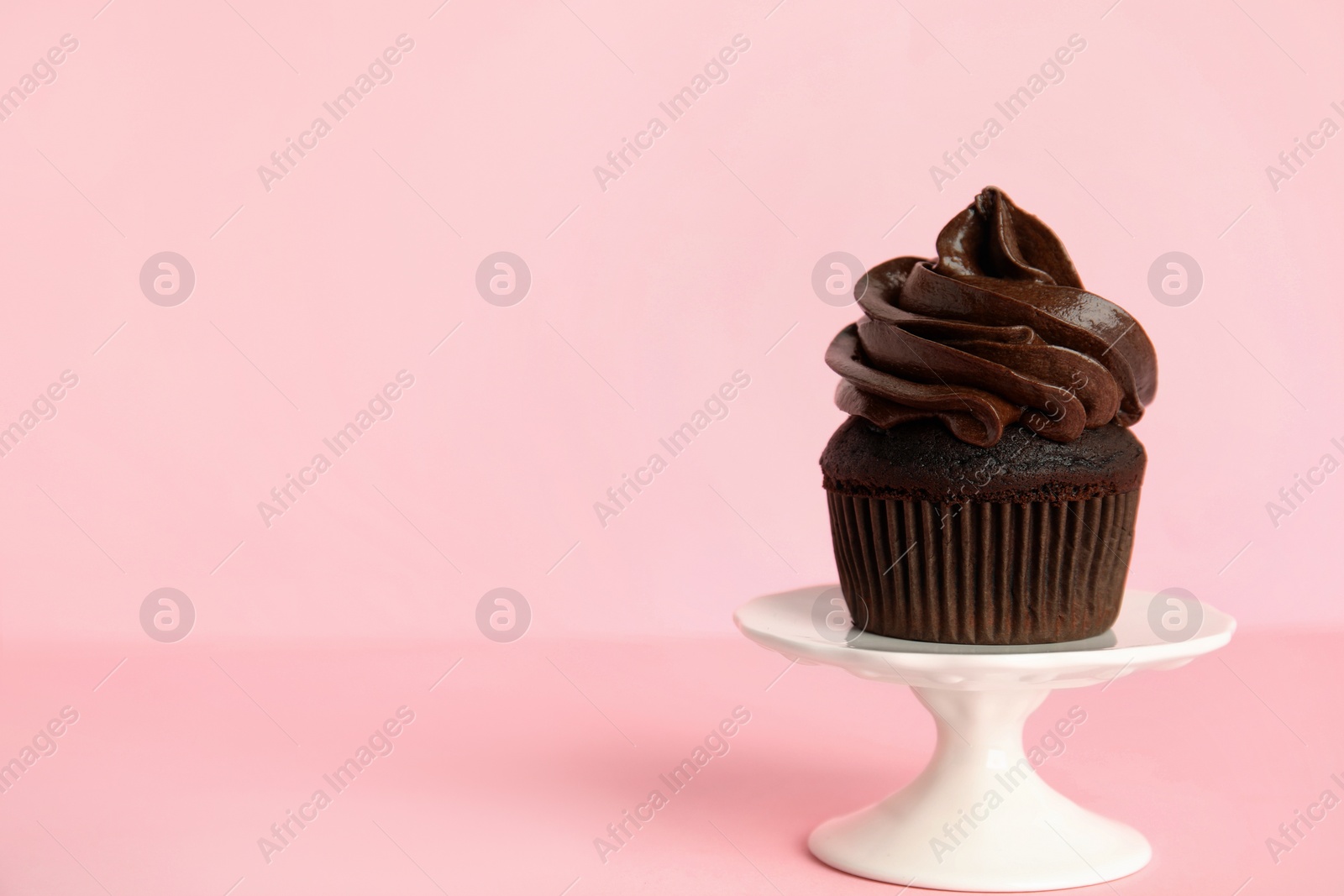 Photo of Dessert stand with delicious chocolate cupcake on pink background. Space for text