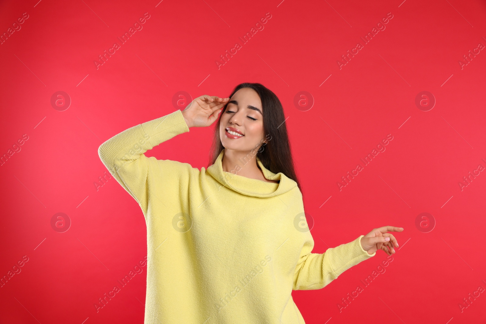 Photo of Beautiful young woman wearing yellow warm sweater on red background