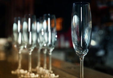 Photo of Empty clean champagne glass on counter in bar, closeup. Space for text