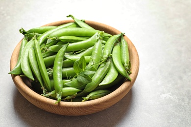 Plate with green peas on light background