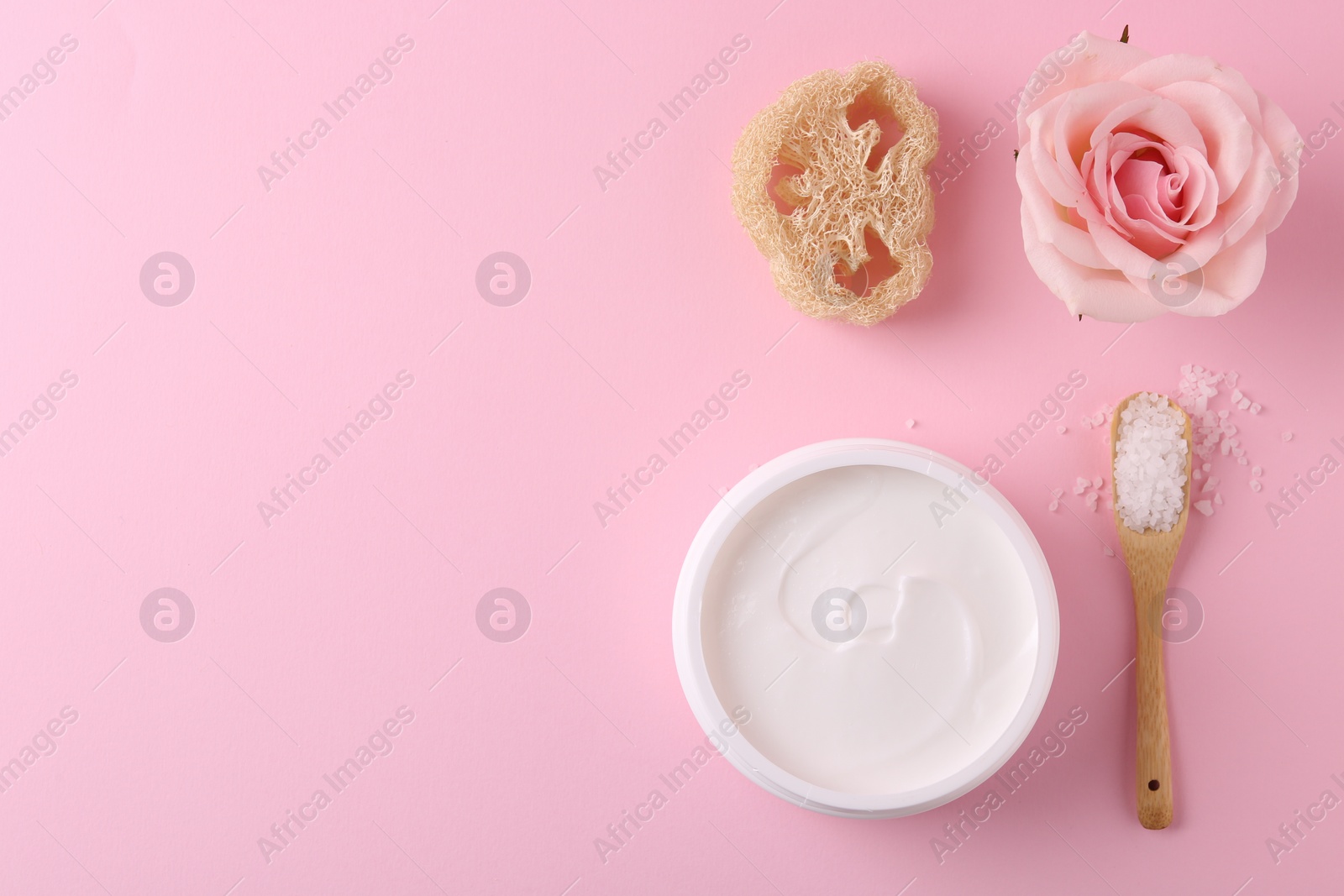 Photo of Jar of cream, sea salt and loofah on pink background, flat lay with space for text. Body care products