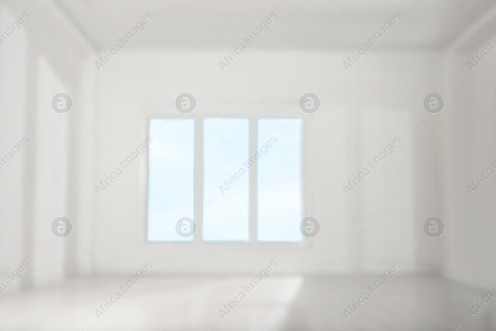 Photo of Empty room with white walls and large window, blurred view