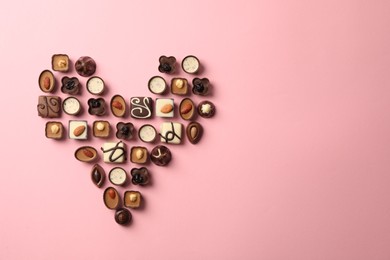 Photo of Heart made with delicious chocolate candies on pink background, top view. Space for text