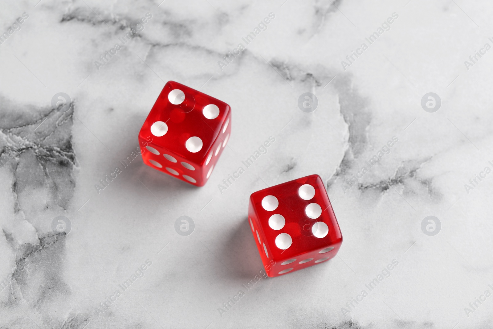 Photo of Two red game dices on white marble table, above view