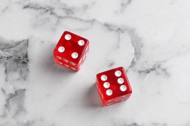 Photo of Two red game dices on white marble table, above view