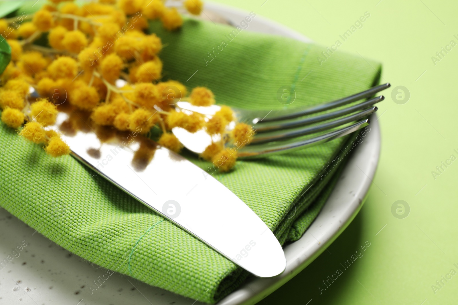 Photo of Festive Easter table setting with floral decor on green background, closeup