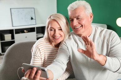 Mature couple using video chat on mobile phone at home