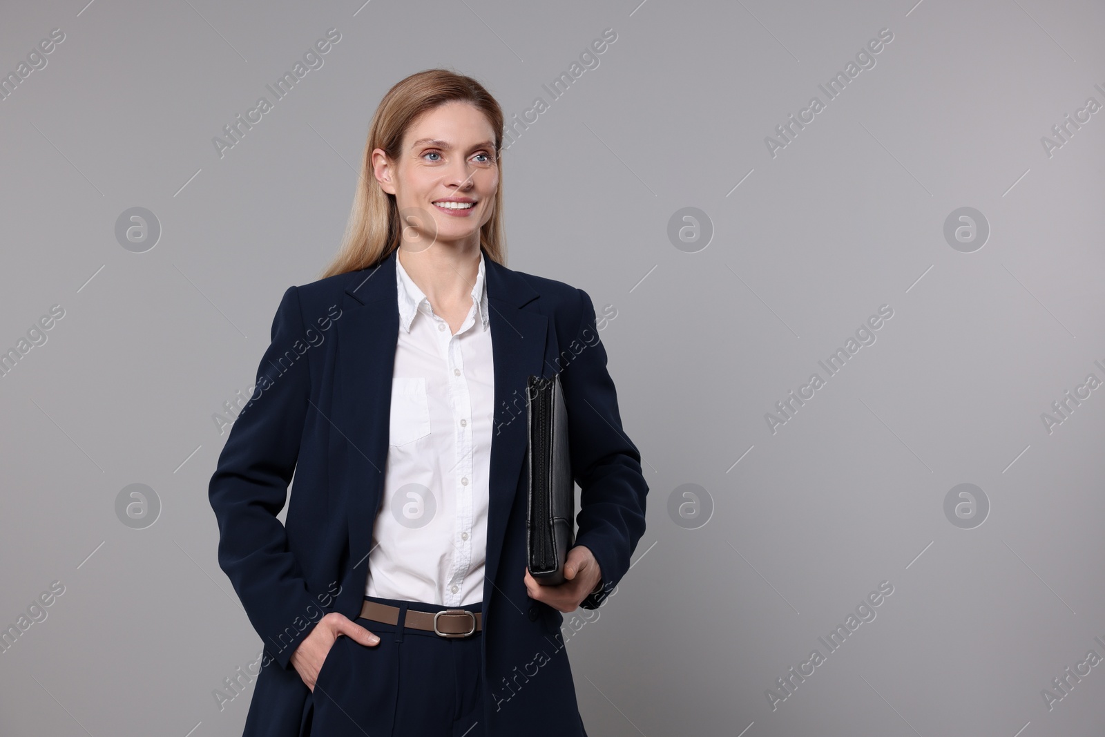 Photo of Happy real estate agent with leather portfolio on grey background. Space for text