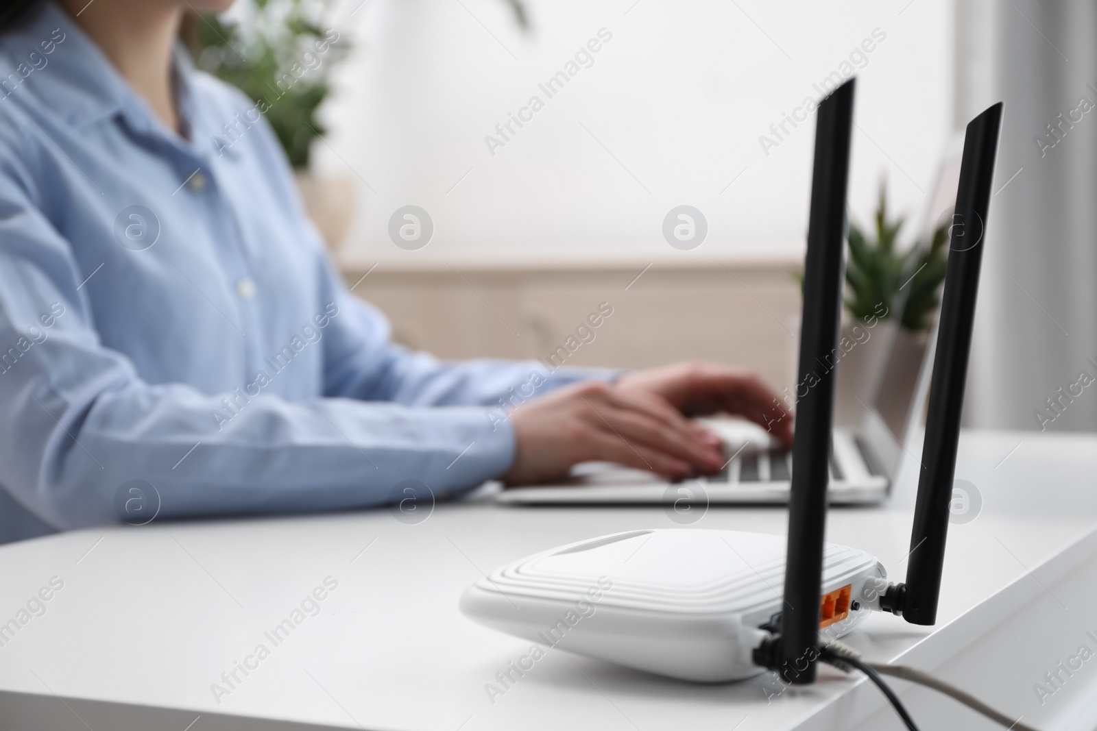 Photo of Woman working in office, focus on connected with cable router. Wireless internet communication