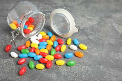 Overturned jar with jelly beans on stone background. Space for text