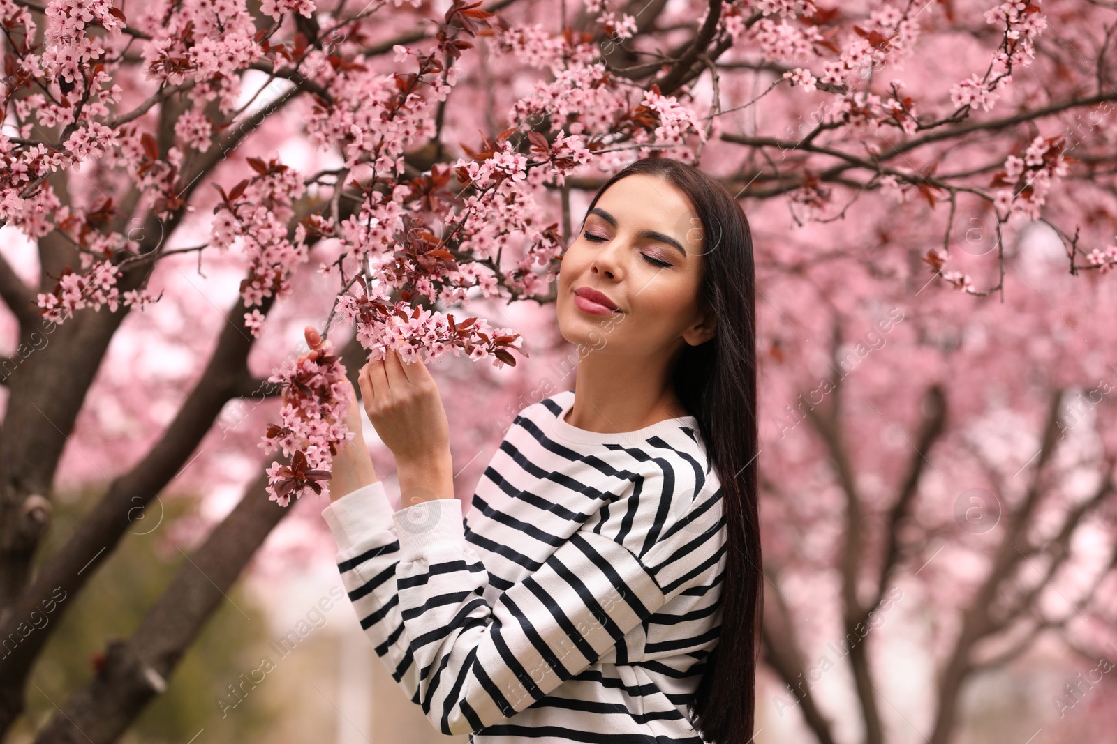 Photo of Pretty young woman near blooming tree in park. Spring look