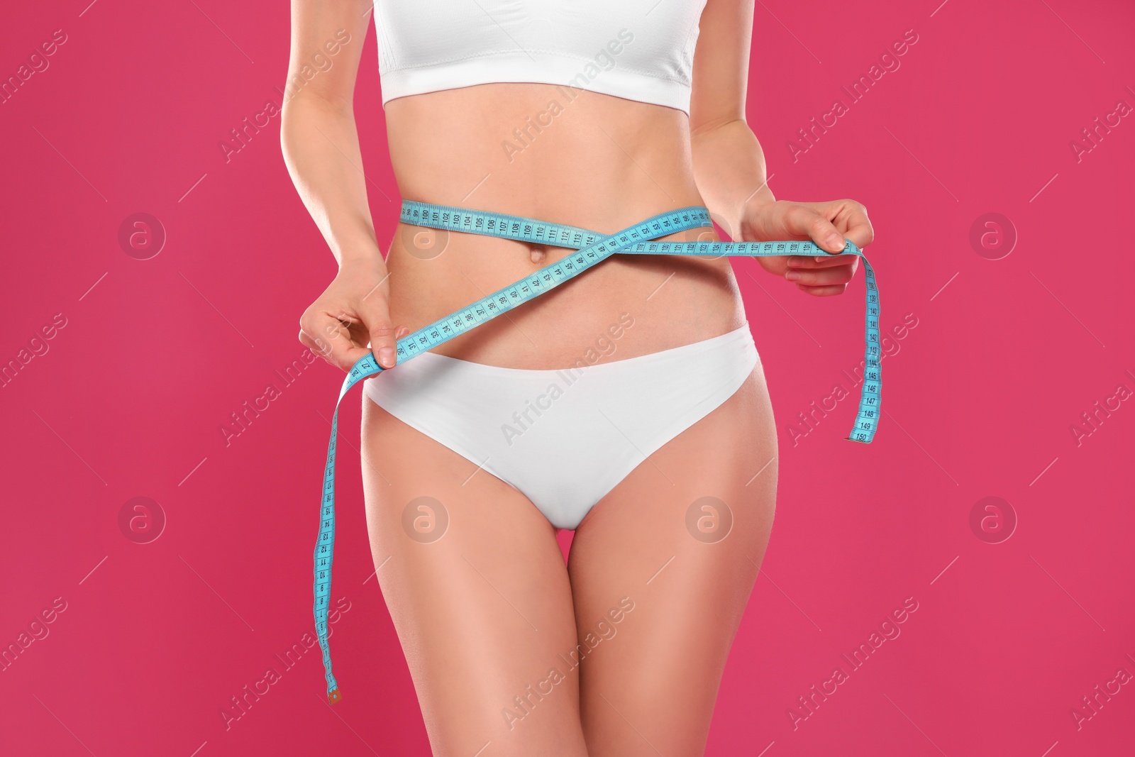 Photo of Slim young woman with smooth gentle skin in underwear measuring body on color background, closeup