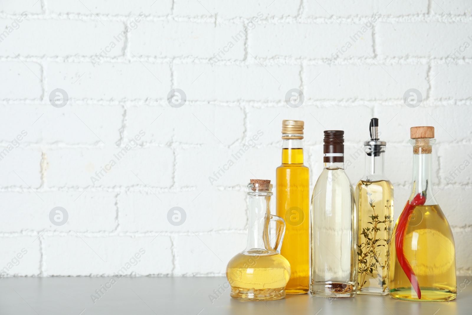 Photo of Different cooking oils on grey table. Space for text