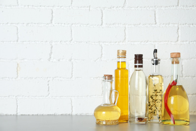 Photo of Different cooking oils on grey table. Space for text