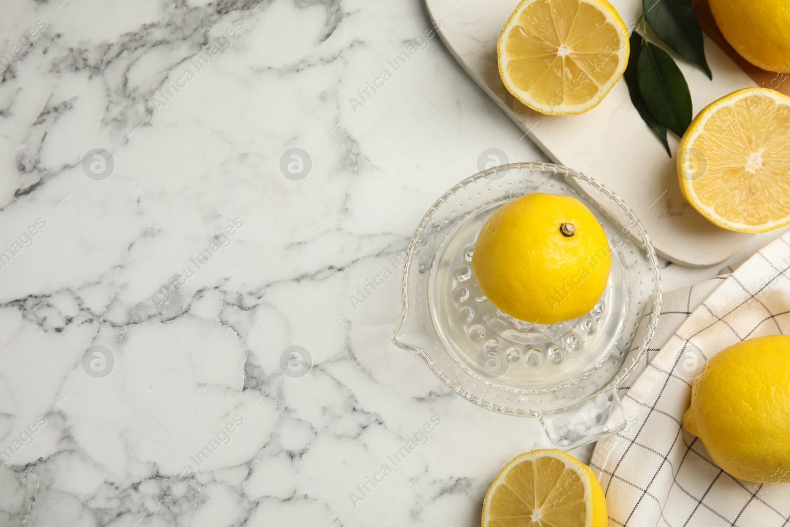 Photo of Glass squeezer and fresh lemons on white marble table, flat lay. Space for text