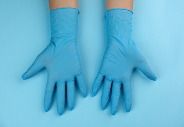Photo of Person in medical gloves on light blue background, top view