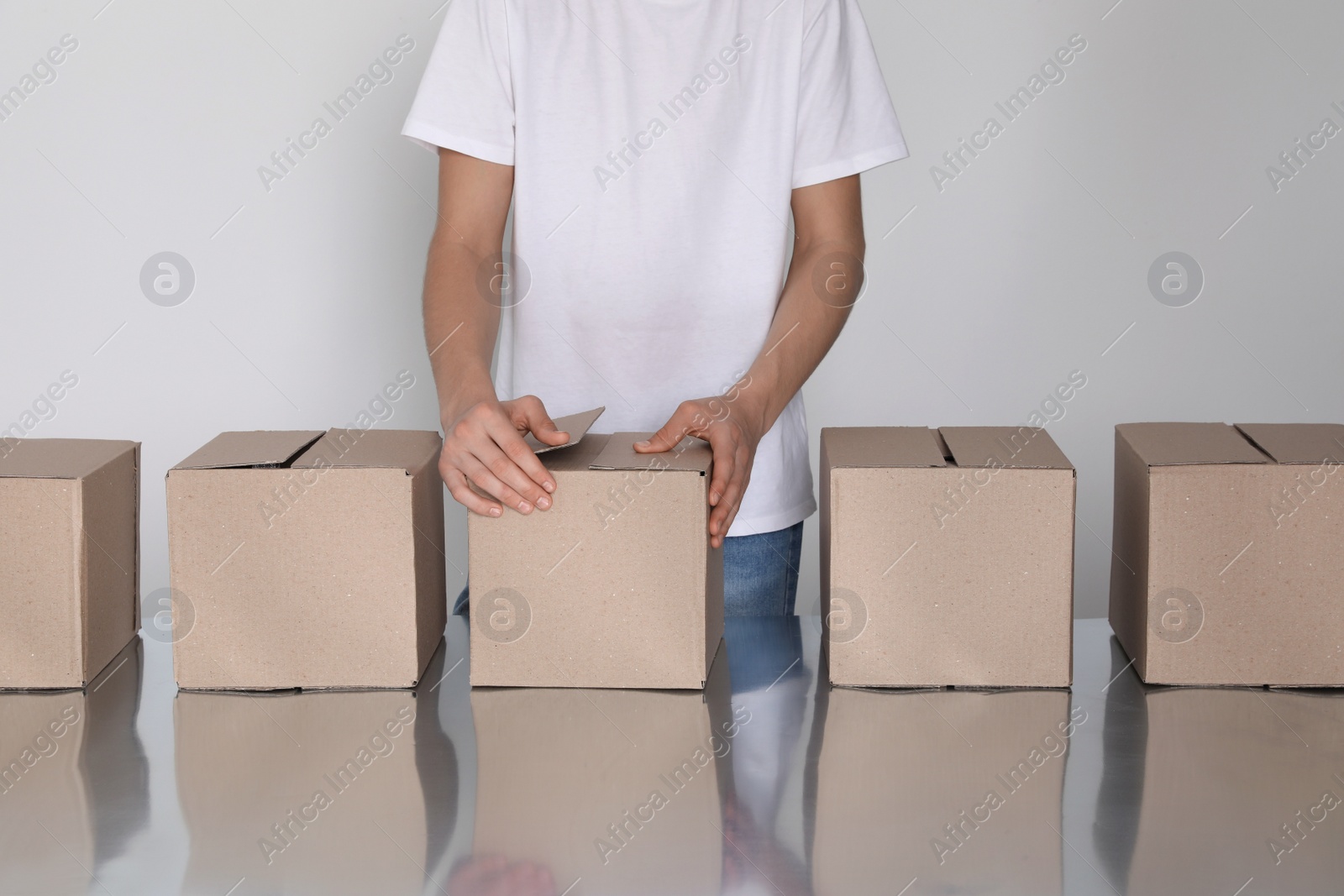 Photo of Man folding cardboard boxes at table, closeup. Production line