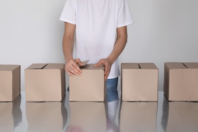 Photo of Man folding cardboard boxes at table, closeup. Production line