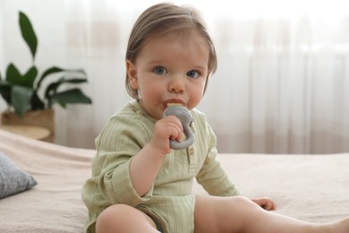 Photo of Cute baby girl with nibbler on bed at home