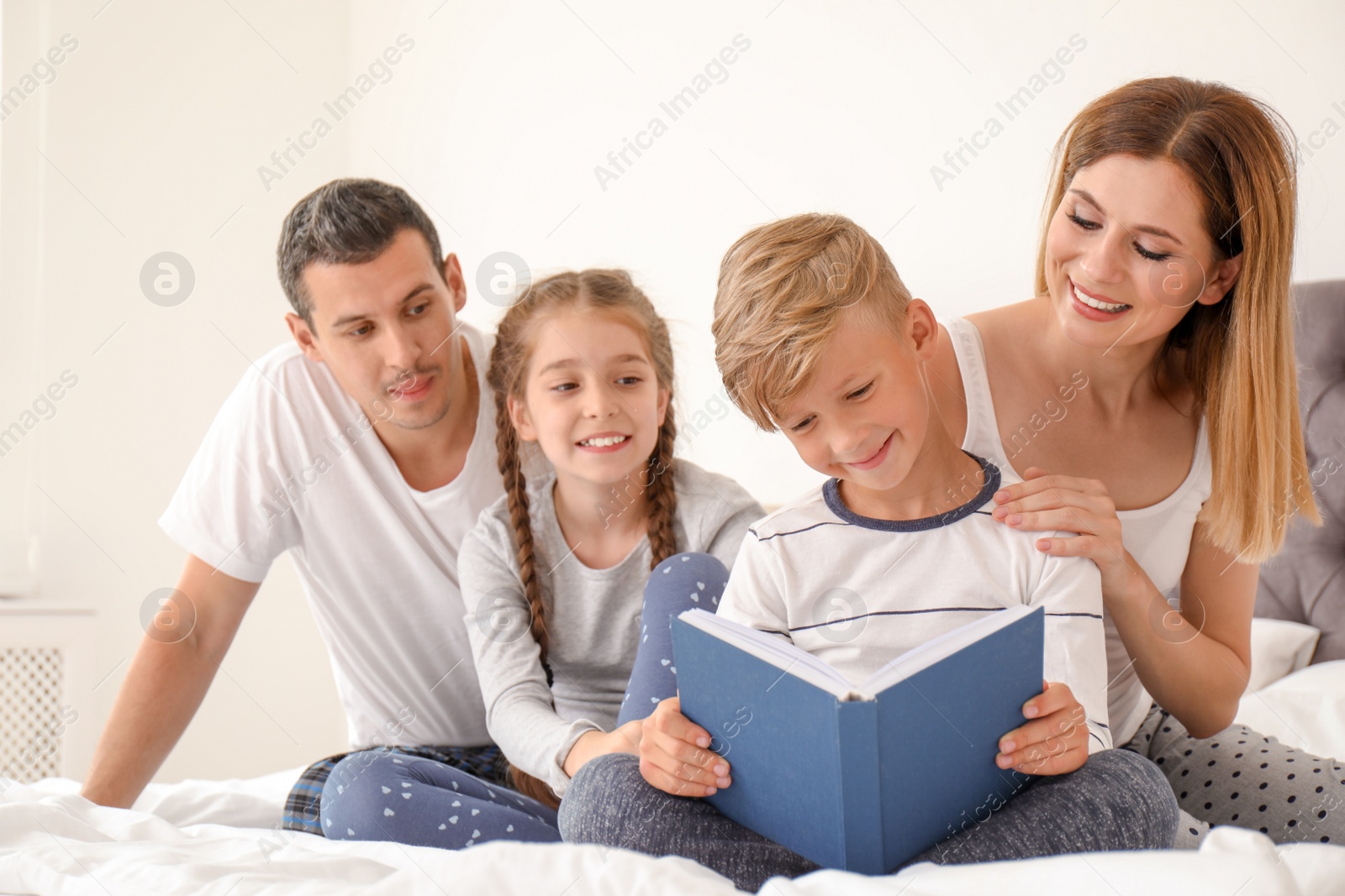 Photo of Child reading book to family in bedroom. Spending time together