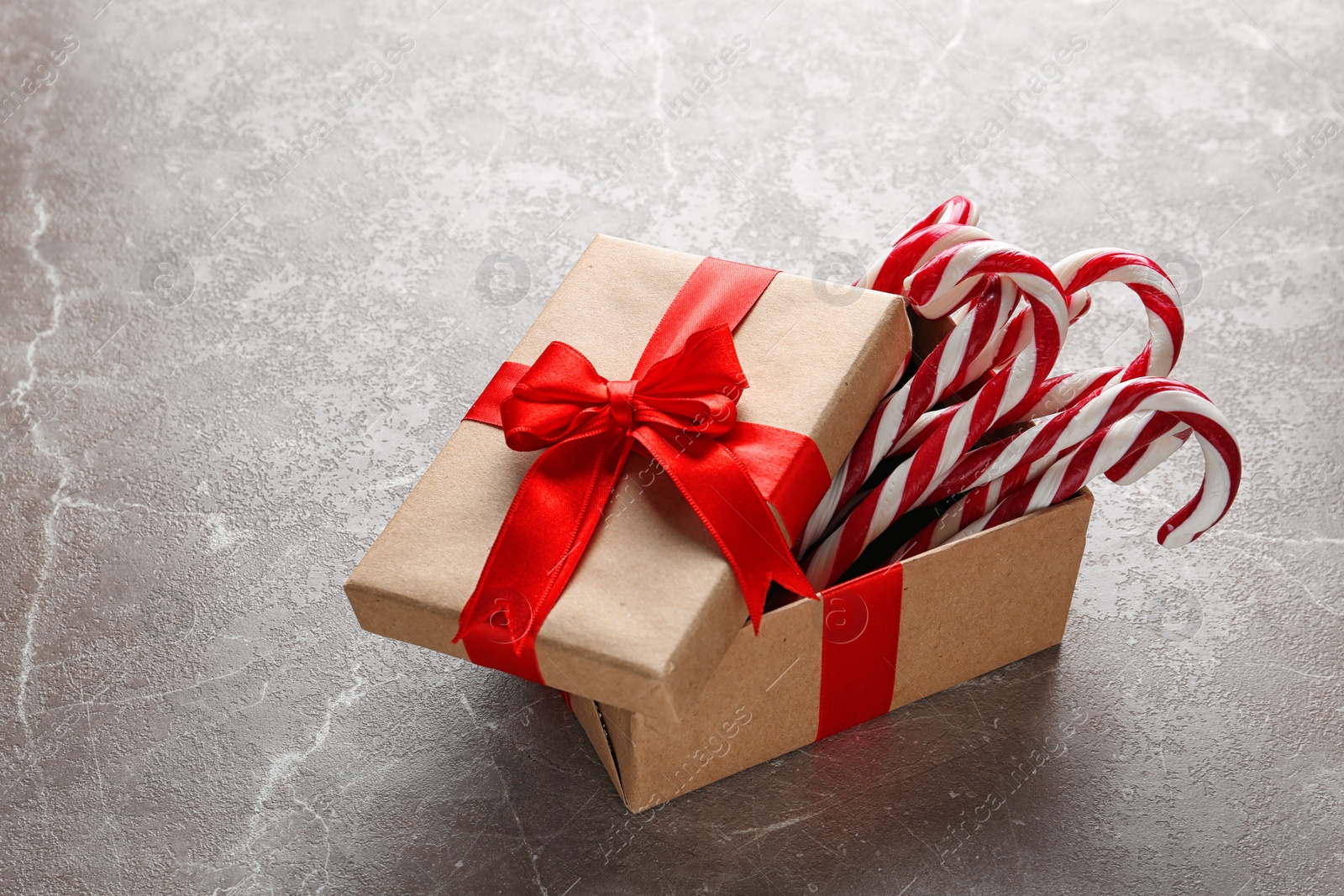 Photo of Candy canes in gift box on light grey marble table. Traditional Christmas treat