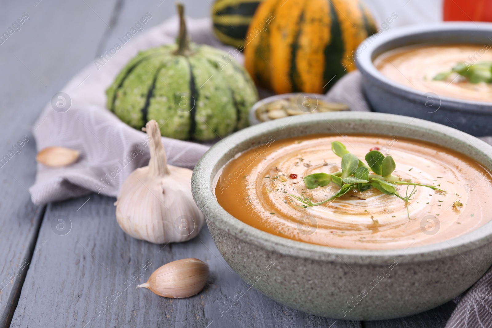 Photo of Delicious pumpkin soup served on gray wooden table, closeup