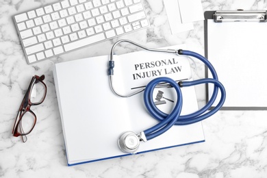 Photo of Flat lay composition with book, stethoscope and computer keyboard on marble background. Personal injury law concept