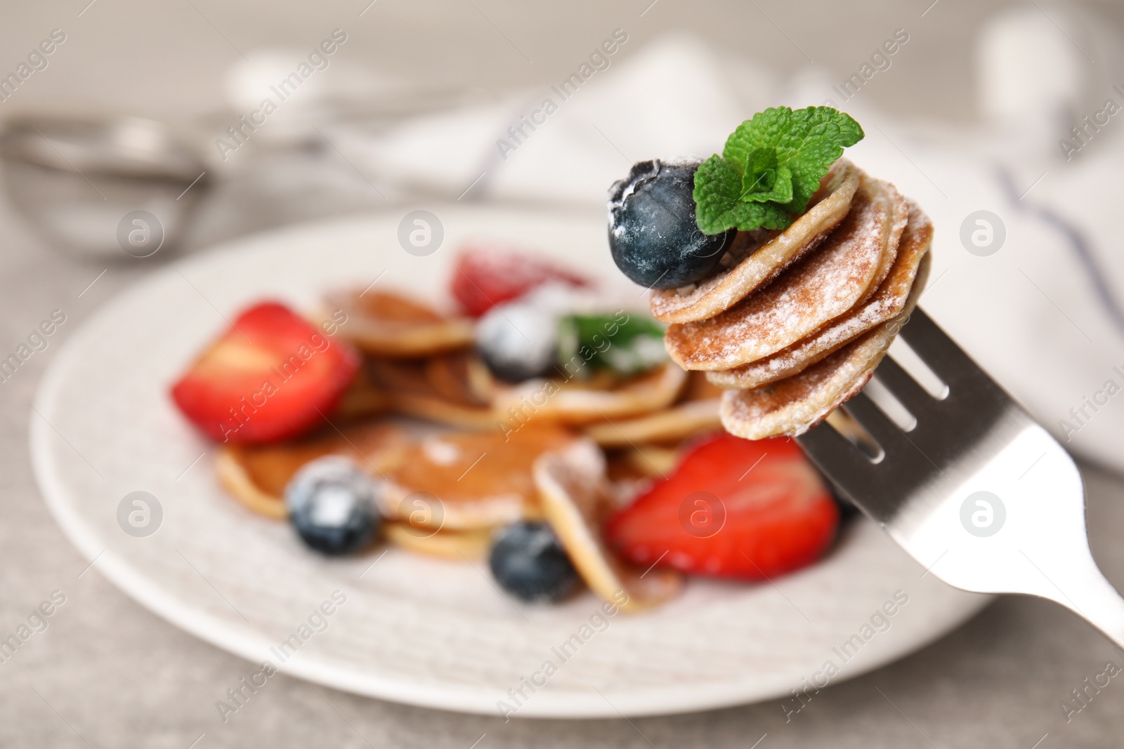 Photo of Fork with cereal pancakes, blueberry and mint on blurred background, closeup. Space for text