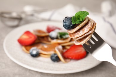 Photo of Fork with cereal pancakes, blueberry and mint on blurred background, closeup. Space for text