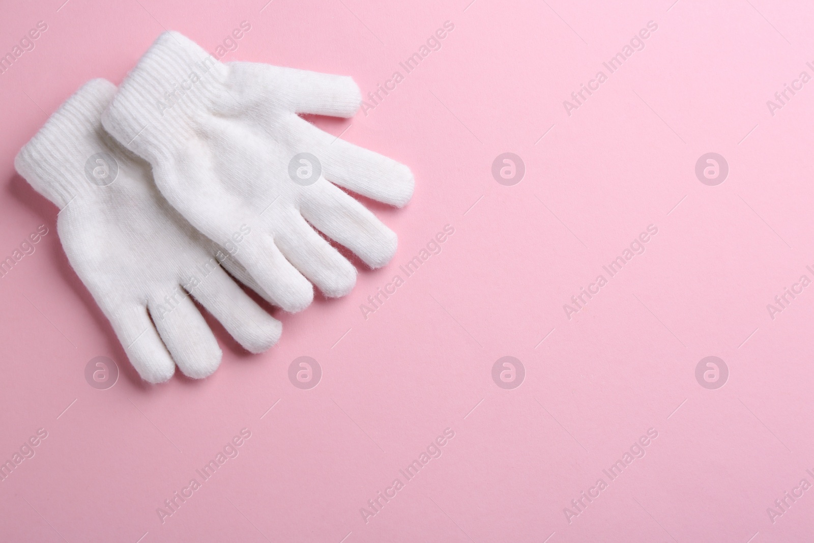 Photo of Pair of stylish woolen gloves on pink background, flat lay. Space for text