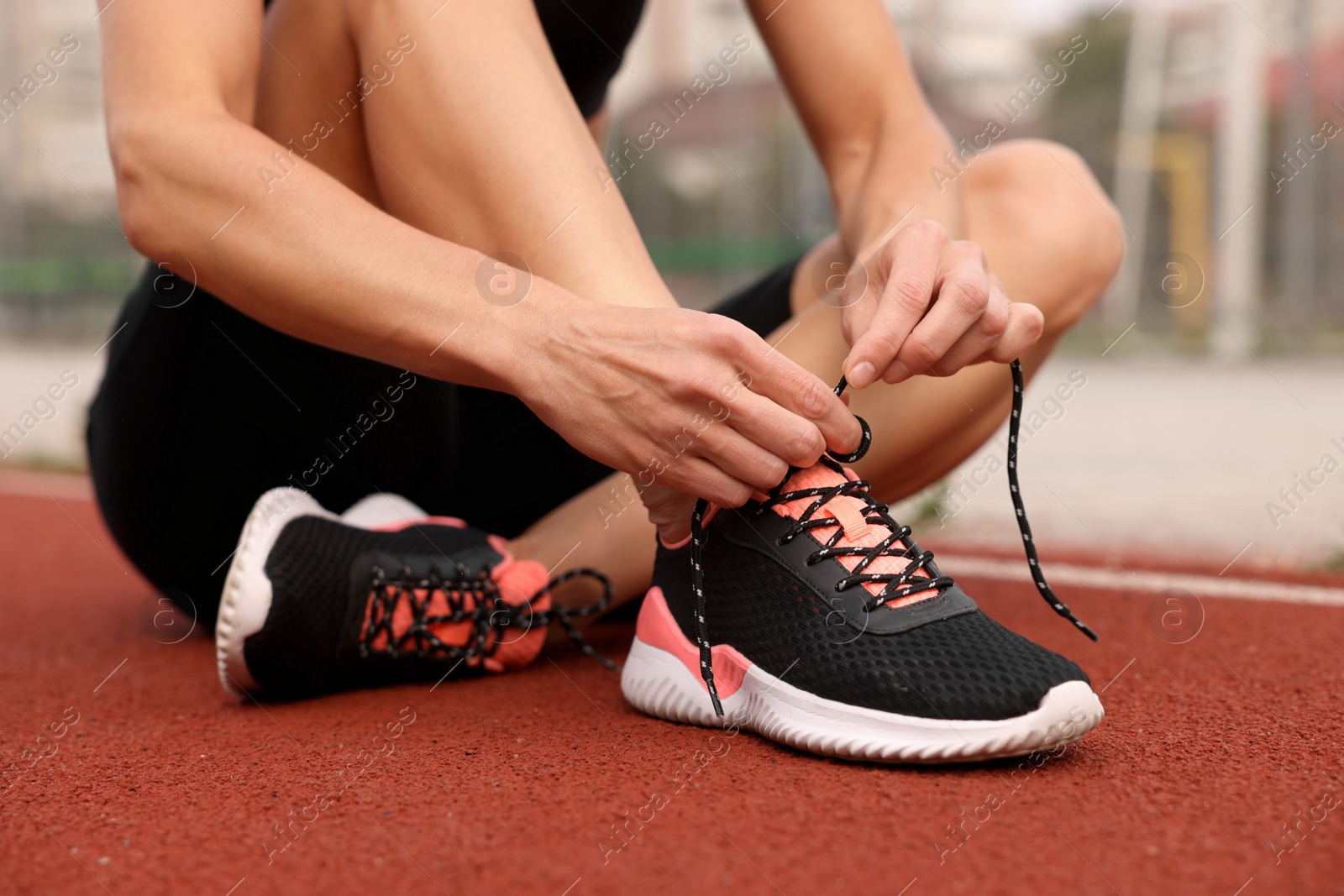 Photo of Woman tying shoelaces before training outdoors, closeup