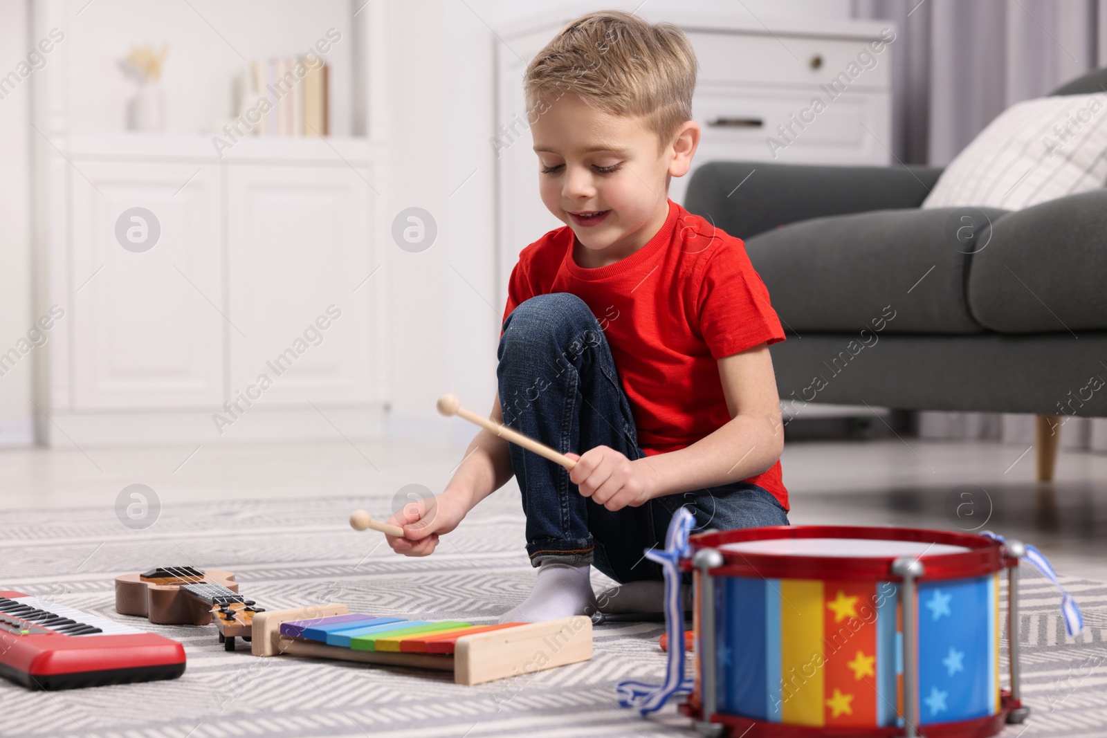 Photo of Little boy playing toy xylophone at home