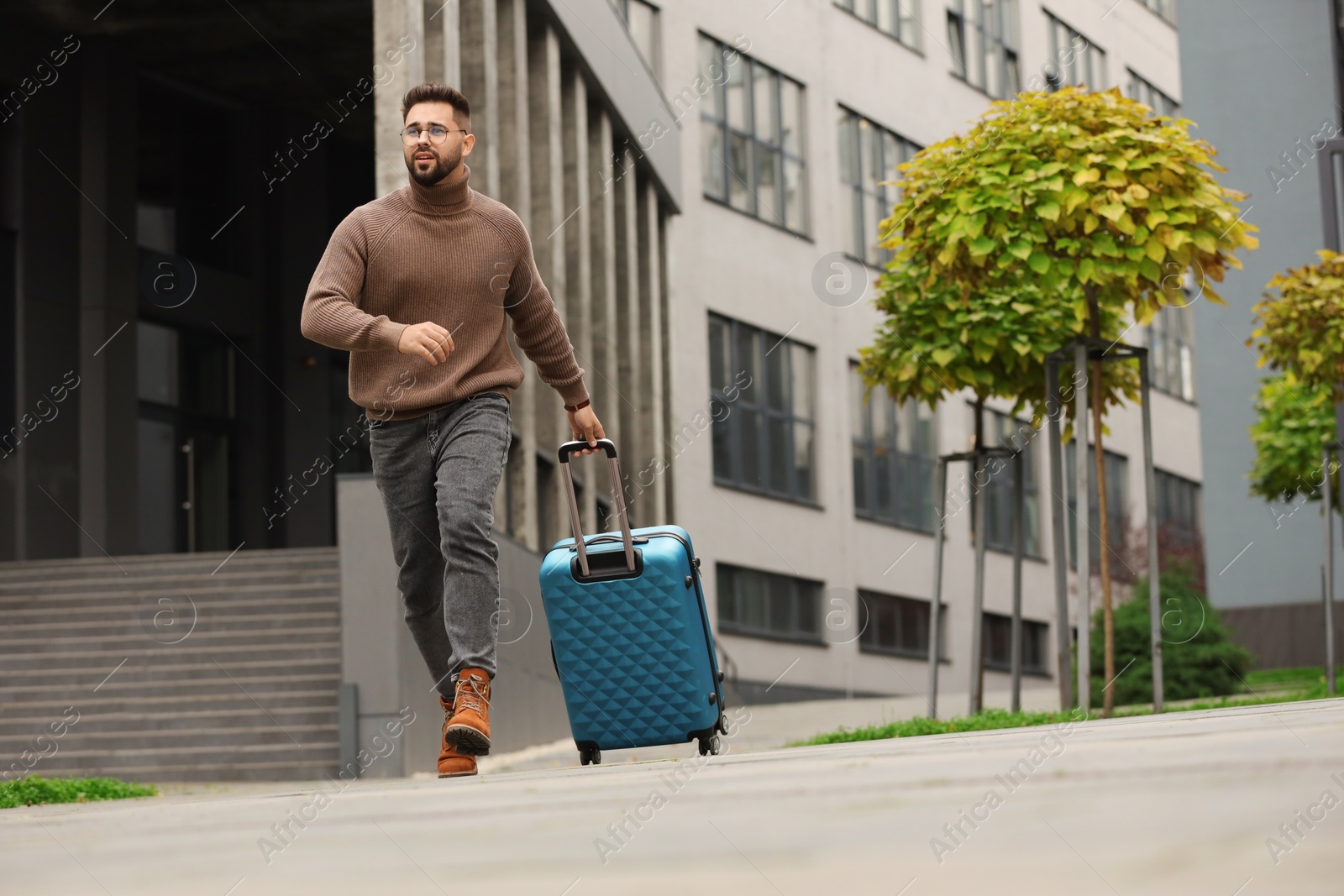 Photo of Being late. Worried man with suitcase running outdoors, space for text