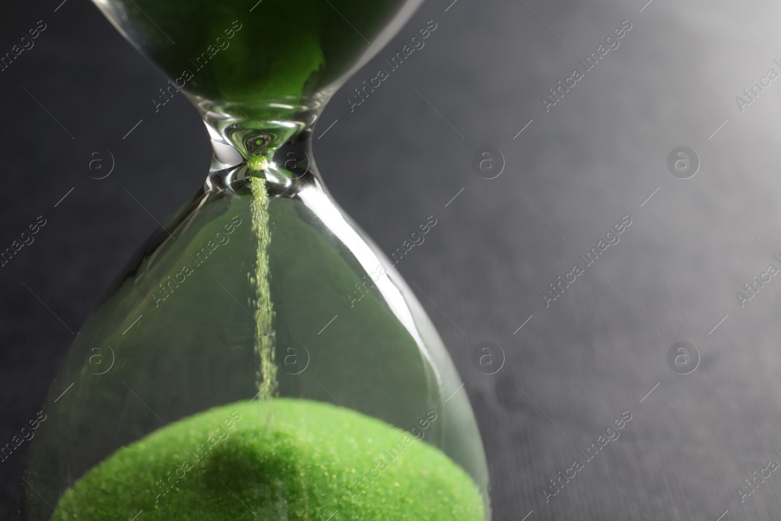 Photo of Hourglass with flowing sand on grey background, closeup. Time management