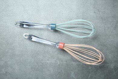 Two whisks on gray table, top view