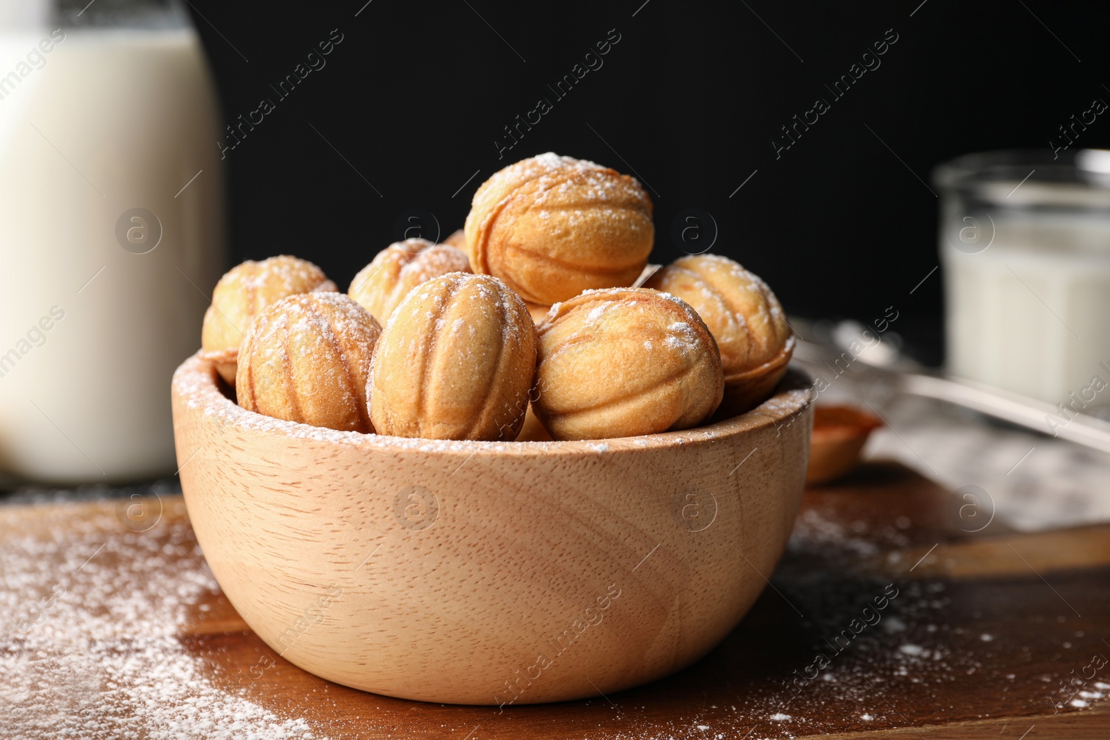 Photo of Delicious nut shaped cookies with powdered sugar on wooden table, closeup. Space for text