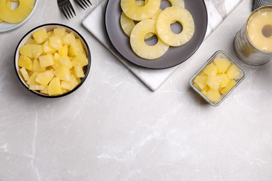 Photo of Flat lay composition with canned pineapple on light grey marble table. Space for text