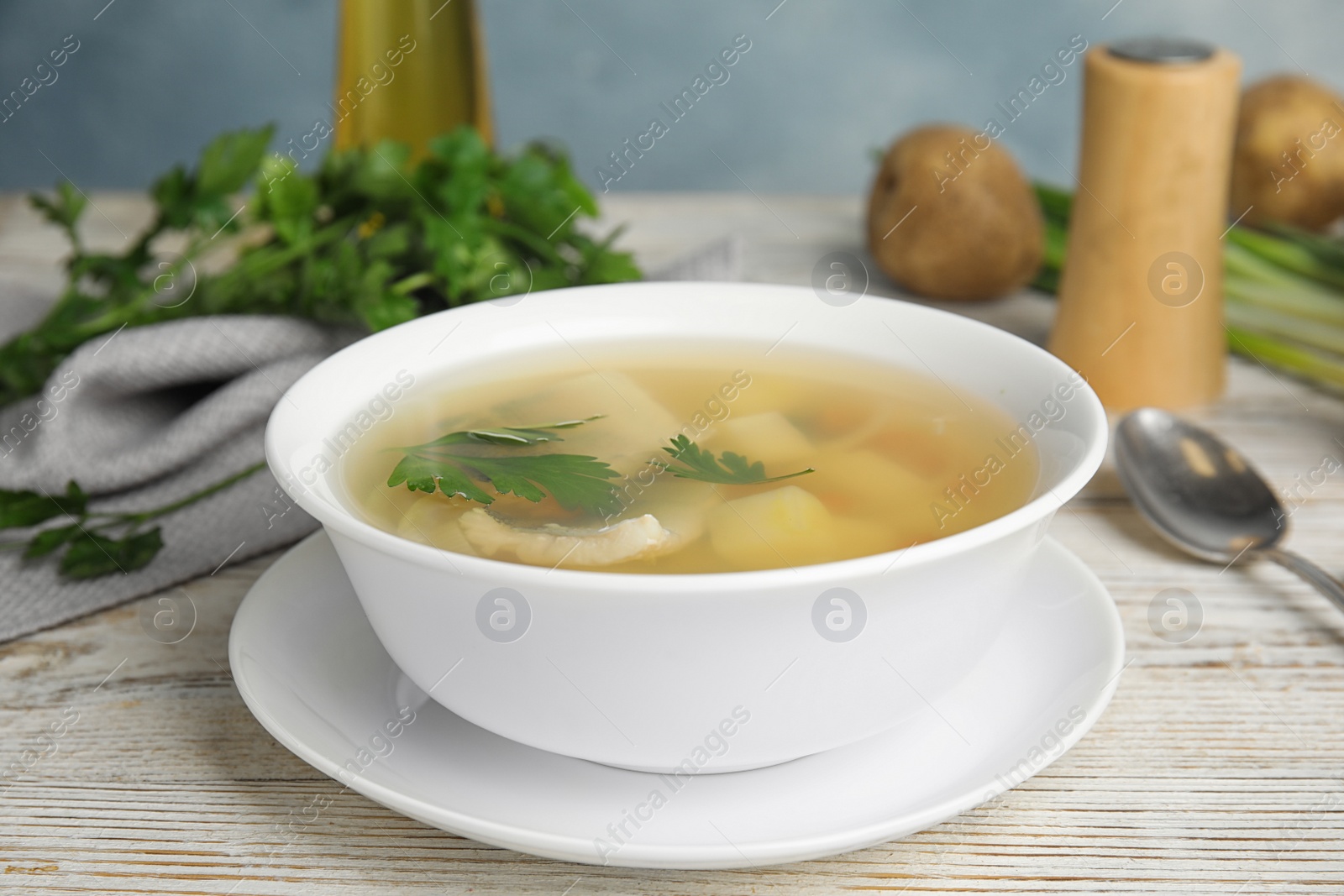 Photo of Delicious fish soup in bowl on white wooden table