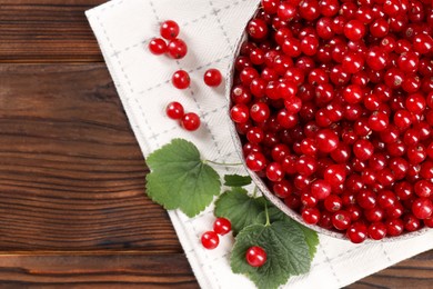 Photo of Ripe red currants and leaves on wooden table, flat lay. Space for text