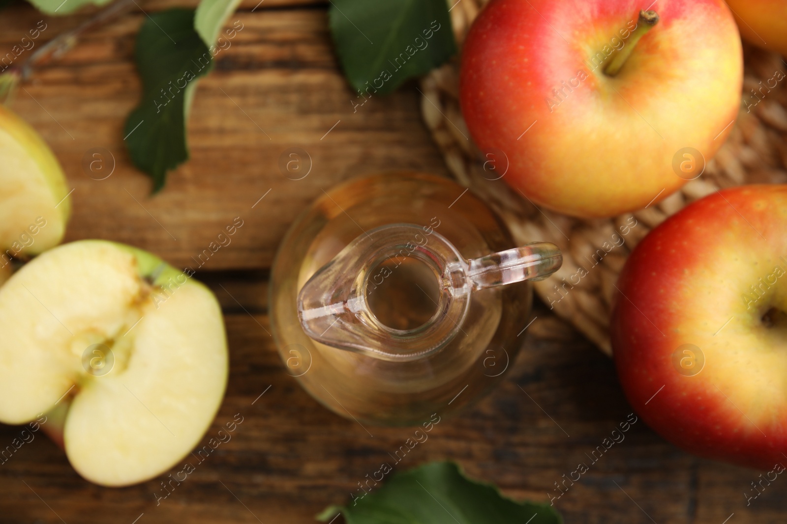 Photo of Natural apple vinegar and fresh fruits on wooden table, flat lay