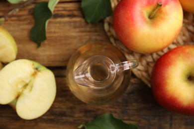 Photo of Natural apple vinegar and fresh fruits on wooden table, flat lay