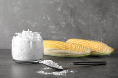 Photo of Jar and spoon with corn starch on table. Space for text