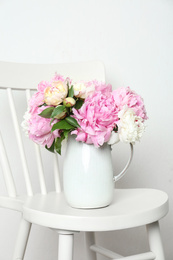 Photo of Beautiful fragrant peonies in jug on white chair