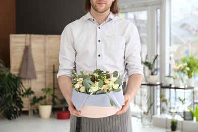 Photo of Male florist holding box with flowers at workplace