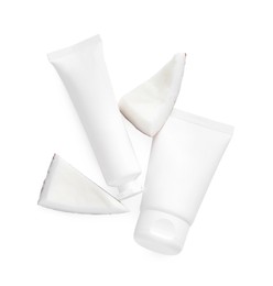 Photo of Tubes of hand cream and coconut pieces on white background, top view